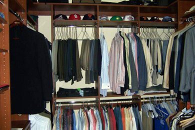 Example of a mid-sized gender-neutral walk-in closet design in Tampa with raised-panel cabinets and medium tone wood cabinets