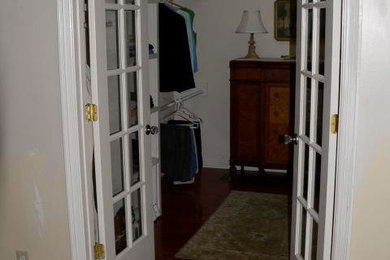 Inspiration for a mid-sized women's dark wood floor walk-in closet remodel in Charlotte with white cabinets