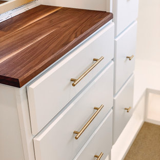 Idee per un armadio incassato unisex country di medie dimensioni con ante con bugna sagomata, ante bianche, moquette, pavimento beige e soffitto in legno