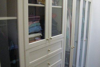 Modelo de armario vestidor tradicional renovado de tamaño medio con armarios tipo vitrina, puertas de armario blancas, suelo de madera oscura y suelo marrón