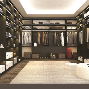 Idee per una grande cabina armadio unisex moderna con ante lisce, ante in legno bruno, parquet scuro e pavimento marrone