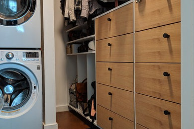 Foto de armario vestidor unisex minimalista pequeño con armarios con paneles lisos, puertas de armario de madera clara, suelo de cemento y suelo marrón