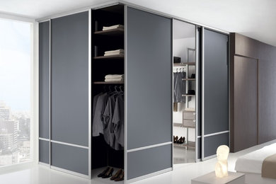Imagen de armario vestidor unisex moderno grande con armarios abiertos, puertas de armario de madera oscura y suelo blanco