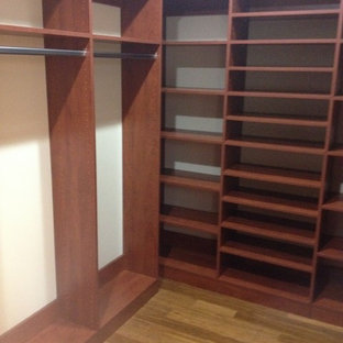 Diseño de armario vestidor unisex, tradicional, de tamaño medio, con puertas de armario de madera oscura, armarios abiertos y suelo de madera clara