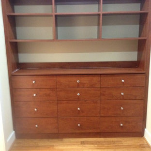 Example of a mid-sized classic gender-neutral light wood floor walk-in closet design in Other with flat-panel cabinets and medium tone wood cabinets