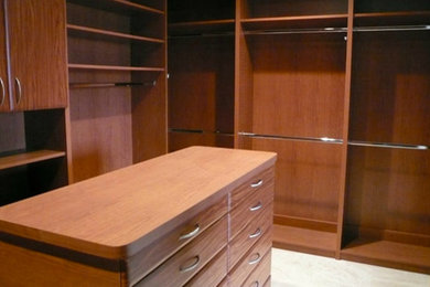 Mid-sized trendy gender-neutral carpeted and beige floor walk-in closet photo in Other with flat-panel cabinets and medium tone wood cabinets