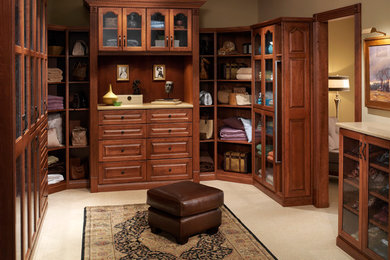 Dressing room - large traditional gender-neutral carpeted and beige floor dressing room idea in Charleston with glass-front cabinets and dark wood cabinets