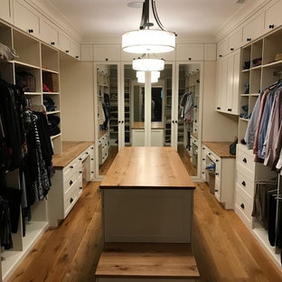Diseño de armario vestidor unisex, campestre, con armarios estilo shaker, puertas de armario blancas y suelo de madera en tonos medios