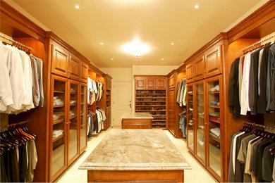 Example of a large arts and crafts men's ceramic tile walk-in closet design in Los Angeles with raised-panel cabinets and medium tone wood cabinets