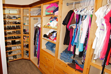 Mid-sized women's carpeted walk-in closet photo in Other with light wood cabinets