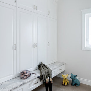 Esempio di una grande cabina armadio chic con ante con bugna sagomata, ante bianche, pavimento in gres porcellanato e pavimento beige