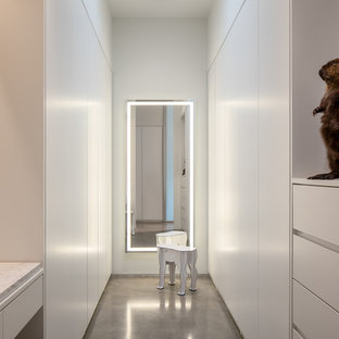 Ejemplo de vestidor unisex, moderno, con armarios con paneles lisos, puertas de armario blancas, suelo de cemento y suelo gris
