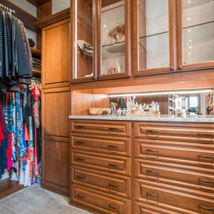 Ejemplo de armario vestidor unisex, clásico, de tamaño medio, con armarios con paneles con relieve, puertas de armario de madera oscura, moqueta y suelo beige