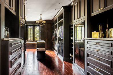 Inspiration for a large timeless men's medium tone wood floor walk-in closet remodel in New York with dark wood cabinets and recessed-panel cabinets
