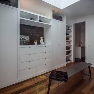Diseño de armario vestidor unisex, contemporáneo, grande, con armarios con paneles lisos, puertas de armario blancas, suelo de madera en tonos medios y suelo marrón
