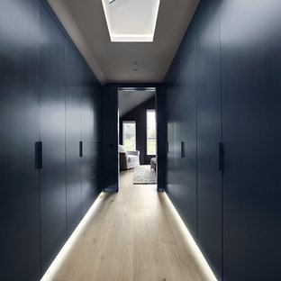 Inspiration för ett stort funkis walk-in-closet, med släta luckor, blå skåp och ljust trägolv