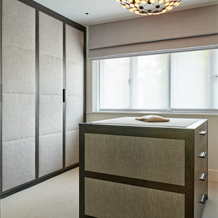 Inspiration for a medium sized contemporary gender neutral dressing room in London with raised-panel cabinets, dark wood cabinets, carpet and beige floors.