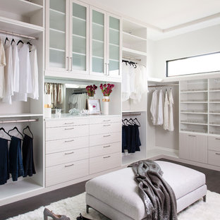 Immagine di un'ampia cabina armadio unisex minimal con ante bianche, parquet scuro, pavimento marrone e ante lisce
