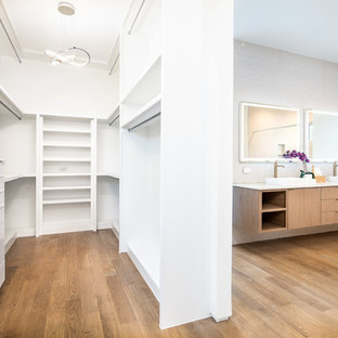 Foto di una cabina armadio unisex minimalista di medie dimensioni con nessun'anta, ante bianche, pavimento in legno massello medio e pavimento marrone