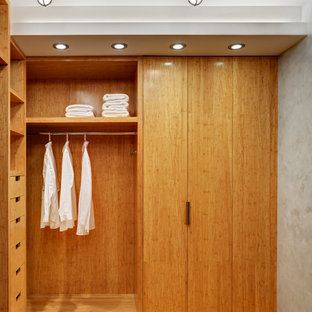 Réalisation d'un petit dressing design neutre avec un placard sans porte, des portes de placard en bois clair et un sol en bambou.