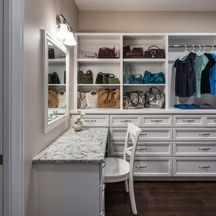 Réalisation d'un grand dressing room craftsman neutre avec un placard avec porte à panneau encastré, des portes de placard blanches, un sol en bois foncé et un sol marron.