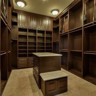 Foto di una grande cabina armadio unisex chic con ante con bugna sagomata, ante marroni, pavimento in travertino e pavimento beige