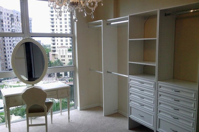 Medium sized traditional walk-in wardrobe for women in Miami with recessed-panel cabinets, white cabinets, carpet and beige floors.