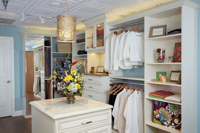 This is an example of a medium sized traditional gender neutral walk-in wardrobe in Other with raised-panel cabinets, white cabinets and dark hardwood flooring.