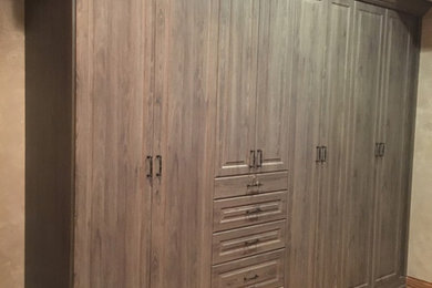 Foto de armario unisex tradicional de tamaño medio con armarios con paneles con relieve, puertas de armario de madera oscura y suelo de madera clara