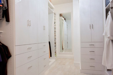Diseño de armario vestidor unisex moderno con armarios con paneles lisos, puertas de armario blancas y suelo de baldosas de porcelana