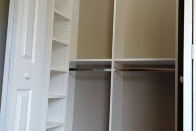 Diseño de armario unisex tradicional pequeño con armarios abiertos, puertas de armario blancas, suelo de madera en tonos medios y suelo marrón