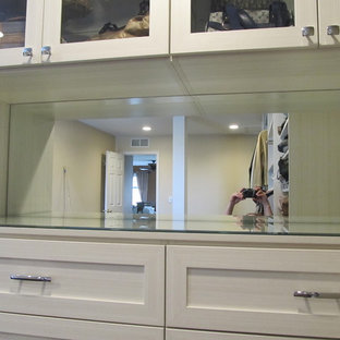 Esempio di una grande cabina armadio con ante di vetro e parquet scuro