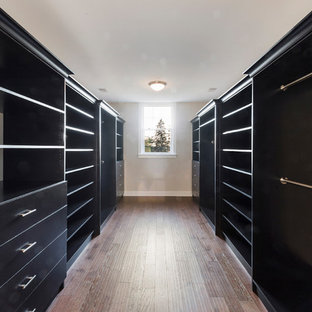 Diseño de armario vestidor unisex, minimalista, de tamaño medio, con armarios abiertos, puertas de armario negras, suelo de madera oscura y suelo marrón