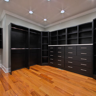 Foto di una grande cabina armadio unisex stile americano con ante lisce, ante nere e pavimento in legno massello medio