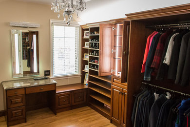 Ejemplo de armario vestidor de mujer ecléctico de tamaño medio con armarios con paneles con relieve, puertas de armario de madera en tonos medios y suelo de madera clara