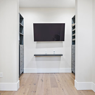 Idéer för att renovera ett funkis walk-in-closet för könsneutrala, med luckor med infälld panel, blå skåp, ljust trägolv och beiget golv