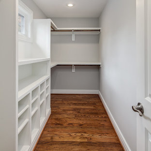 Imagen de armario vestidor unisex, clásico renovado, de tamaño medio, con armarios abiertos, puertas de armario blancas y suelo de madera en tonos medios