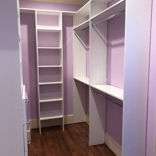 Immagine di una cabina armadio unisex classica di medie dimensioni con ante lisce, ante bianche, pavimento in legno massello medio e pavimento marrone