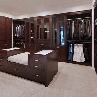 Modelo de vestidor de hombre, clásico renovado, con puertas de armario de madera en tonos medios, moqueta, suelo beige y armarios abiertos