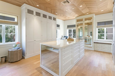 Inspiration for a large transitional gender-neutral light wood floor and beige floor dressing room remodel in Miami with white cabinets