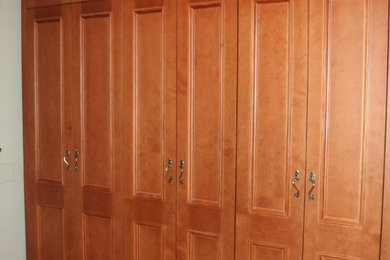 Imagen de armario unisex actual de tamaño medio con armarios con paneles con relieve y puertas de armario de madera oscura