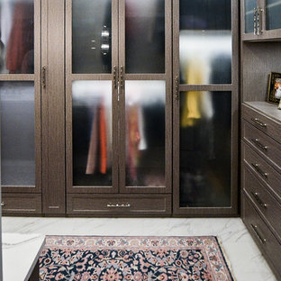 Immagine di un grande spazio per vestirsi unisex con ante di vetro, ante in legno bruno, pavimento in marmo e pavimento bianco