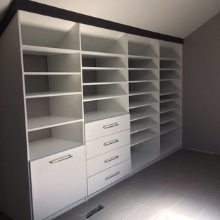 Immagine di un grande spazio per vestirsi design con ante lisce e pavimento in cemento
