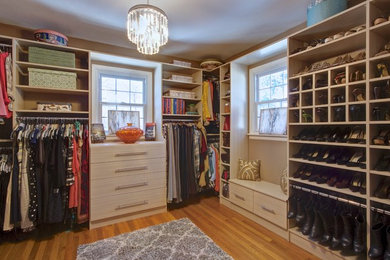 Large modern walk-in wardrobe for women in Other with flat-panel cabinets, light wood cabinets and light hardwood flooring.