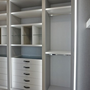 Ejemplo de armario vestidor unisex, minimalista, de tamaño medio, con armarios con paneles lisos, puertas de armario blancas y suelo de madera clara