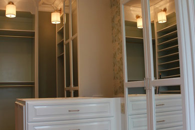 Imagen de armario vestidor unisex clásico grande con armarios tipo vitrina, puertas de armario blancas y suelo de madera oscura