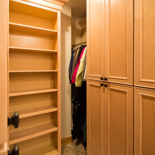 Diseño de armario vestidor unisex, tradicional, grande, con armarios con paneles con relieve, puertas de armario de madera clara, suelo de travertino y suelo beige