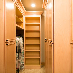 Diseño de armario vestidor unisex, tradicional, grande, con armarios con paneles con relieve, puertas de armario de madera clara, suelo de travertino y suelo beige