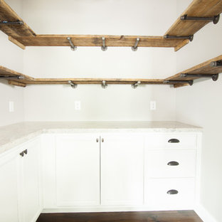 Diseño de armario vestidor de estilo de casa de campo, grande, con puertas de armario blancas y suelo de madera oscura