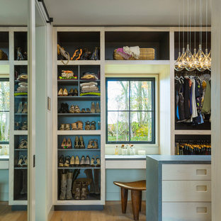 Immagine di una cabina armadio unisex country di medie dimensioni con ante lisce, ante in legno chiaro, pavimento in legno massello medio e pavimento marrone